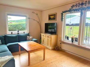 a living room with a blue couch and a tv at Hus Gillberga in Varmlands Nysater