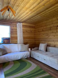a living room with two couches and a wooden ceiling at Деревянный домик in Dolinka