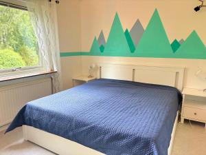 a bedroom with a blue bed with a mountain mural on the wall at Hus Gillberga in Varmlands Nysater