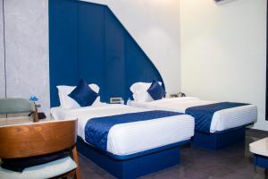 two beds in a room with blue walls at Hotel Orbit in Parbhani