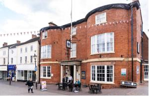 a red brick building with people standing outside of it at The Crown Hotel in Stone