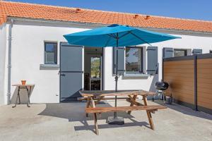 a picnic table with an umbrella in front of a building at La Maison Familiale in Commequiers
