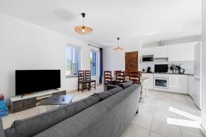 a living room with a large couch and a kitchen at La Maison Familiale in Commequiers