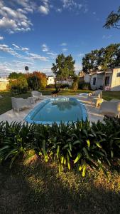 a swimming pool in a yard with chairs and plants at Espacio Canela monoambiente in Ramallo +3 photos