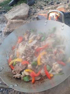 a wok with meat and vegetables cooking on a grill at Safa home in Al Ghuşnah