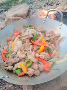 a wok filled with meat and vegetables on a grill at Safa home in Al Ghuşnah