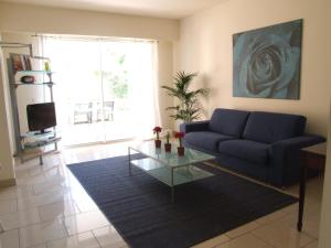 uma sala de estar com um sofá azul e uma mesa de vidro em Appartement au Chateau Vallaya em Menton