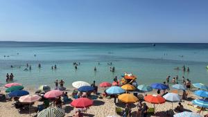 a group of people on a beach with umbrellas at On the Beach in Torre Lapillo