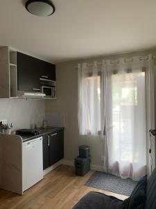 a kitchen with a sink and a window with white curtains at Studio Indépendant in Floirac