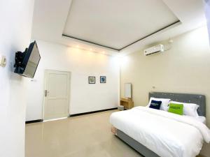 a white bedroom with a bed and a tv at Urbanview Bangsal Mojokerto in Ngranggon