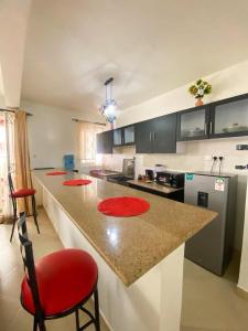 a kitchen with a counter with red chairs and a counter top at jennies staycation in Mombasa +1 photo