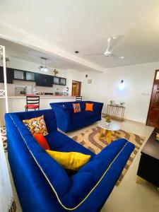 a living room with a blue couch with colorful pillows at jennies staycation in Mombasa