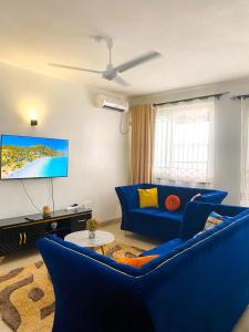 a living room with a blue couch and a tv at jennies staycation in Mombasa