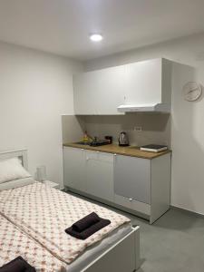 a kitchen with white cabinets and a bed in a room at Apartman Beli Bagrem in Veliko Gradište