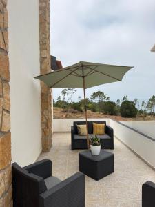 a patio with two couches and an umbrella at Lucas Residence in Nazaré