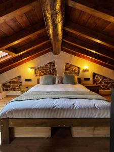 a bedroom with a large bed with wooden ceilings at El Balcón de Urbiés in Mieres