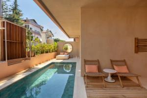 an infinity pool in a house with two chairs and a table at La Gaia - Adult Only in Alanya