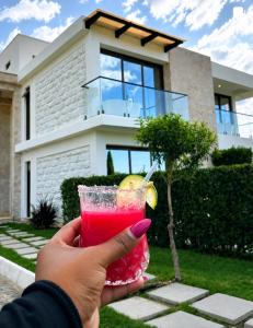 a person holding a drink in front of a house at Flamingo Bay in Nakuru