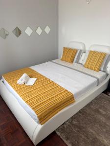a bed with a yellow and white blanket on it at Lucas Residence in Nazaré