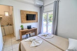 a hotel room with two beds and a television at Ikaria Therma Blue in Agios Kirykos