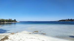 a beach with blue water and trees in the background at Sardinia Re - Grecale 39 in Porto Rotondo