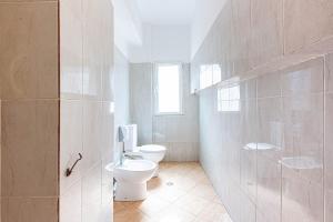 a white bathroom with two toilets and a window at Dhermi's Icon Big 1BR Ap 15 in Dhërmi +2 photos