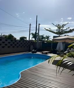 a swimming pool with a wooden deck and an umbrella at Pousada da Mel in Florianópolis