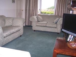 a living room with two chairs and a couch and a television at Feochan View in Oban