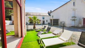 a patio with white chairs and a table on grass at Les 4 AS de Jaunay, Le Cocon, Futuroscope in Jaunay-Clan