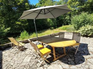 a wooden table and chairs with an umbrella at Maison Le Feu Follet in Lormes
