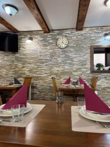 a dining room with a table and a clock on a brick wall at B&B Millenium House in Plitvička Jezera