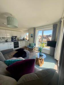 a living room with a couch and a kitchen at Number 15 Luxurious Two Bedroom Apartment - free secure parking in Exmouth