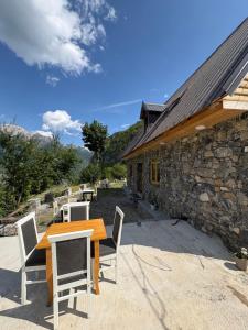 a table and chairs on a patio next to a stone building at Nini Guesthouse Theth in Theth