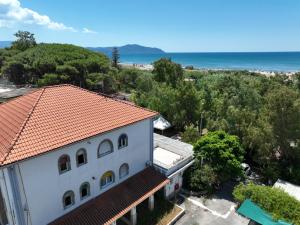 a white building with a red roof and the ocean at Hotel sul Mare e Lido Atena in Paestum