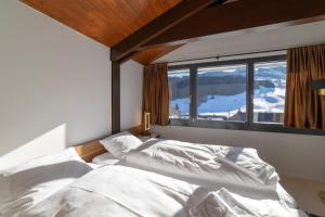 ein Schlafzimmer mit zwei weißen Betten vor einem Fenster in der Unterkunft Alpstern in Wildhaus