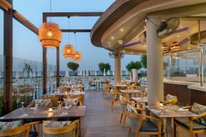 ein Restaurant mit Tischen und Stühlen auf einem Balkon in der Unterkunft Pernera Beach Hotel in Protaras