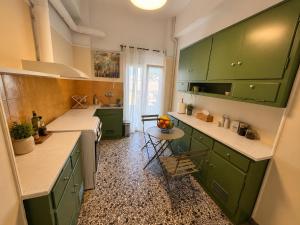 a green kitchen with green cabinets and a table at Central Mytilene City-View Apartment for 7 in Mytilene