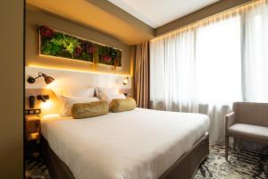 a hotel room with a large bed and a chair at Hôtel B55 in Paris +47 photos