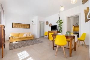 a living room with a dining room table and yellow chairs at Lu Furru Apartments in Telti