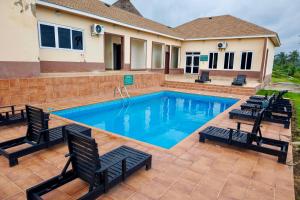 a swimming pool with chairs and a house at Nyansapo Eco Resort in Cape Coast