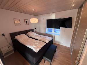 a small bedroom with a bed and a flat screen tv at Arctic Hostel Apartment in Qaqortoq