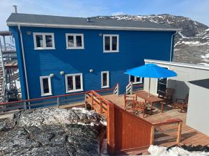 a blue house on a deck with a table and umbrella at Arctic Hostel Apartment in Qaqortoq
