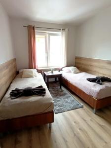 two beds in a room with a window at Hotelik Kościerzyna in Kościerzyna +7 photos