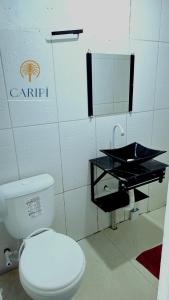 a bathroom with a white toilet and a sink at Suite 02 in Barcarena