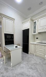 a kitchen with white cabinets and a black refrigerator at Malibo Central Apartments in Baku