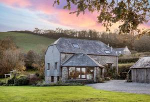 a stone house with a gray roof on a green field at Mowhay Barn in Torpoint