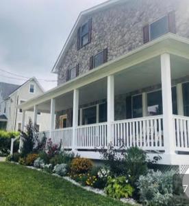 a large house with a white porch and flowers at Naomi BED and BREAKFAST in Parkville