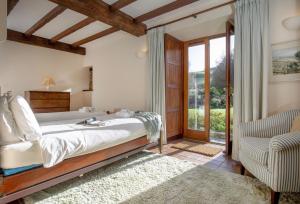 a bedroom with a bed and a chair and a window at Mowhay Barn in Torpoint