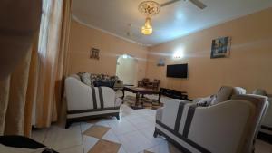 a living room with chairs and a table and a tv at Furaha House in Chukwani