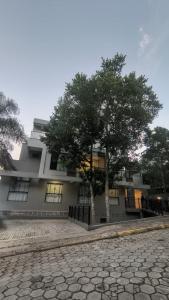a building with a tree in front of it at Villa Parati Bombinhas Sob Nova Direção in Bombinhas